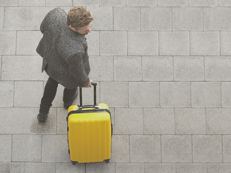 man walking with a yellow suitcase in London provided by Addison Lee